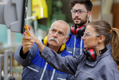 Eine Frau und zwei Männer an einer Produktionsmaschine